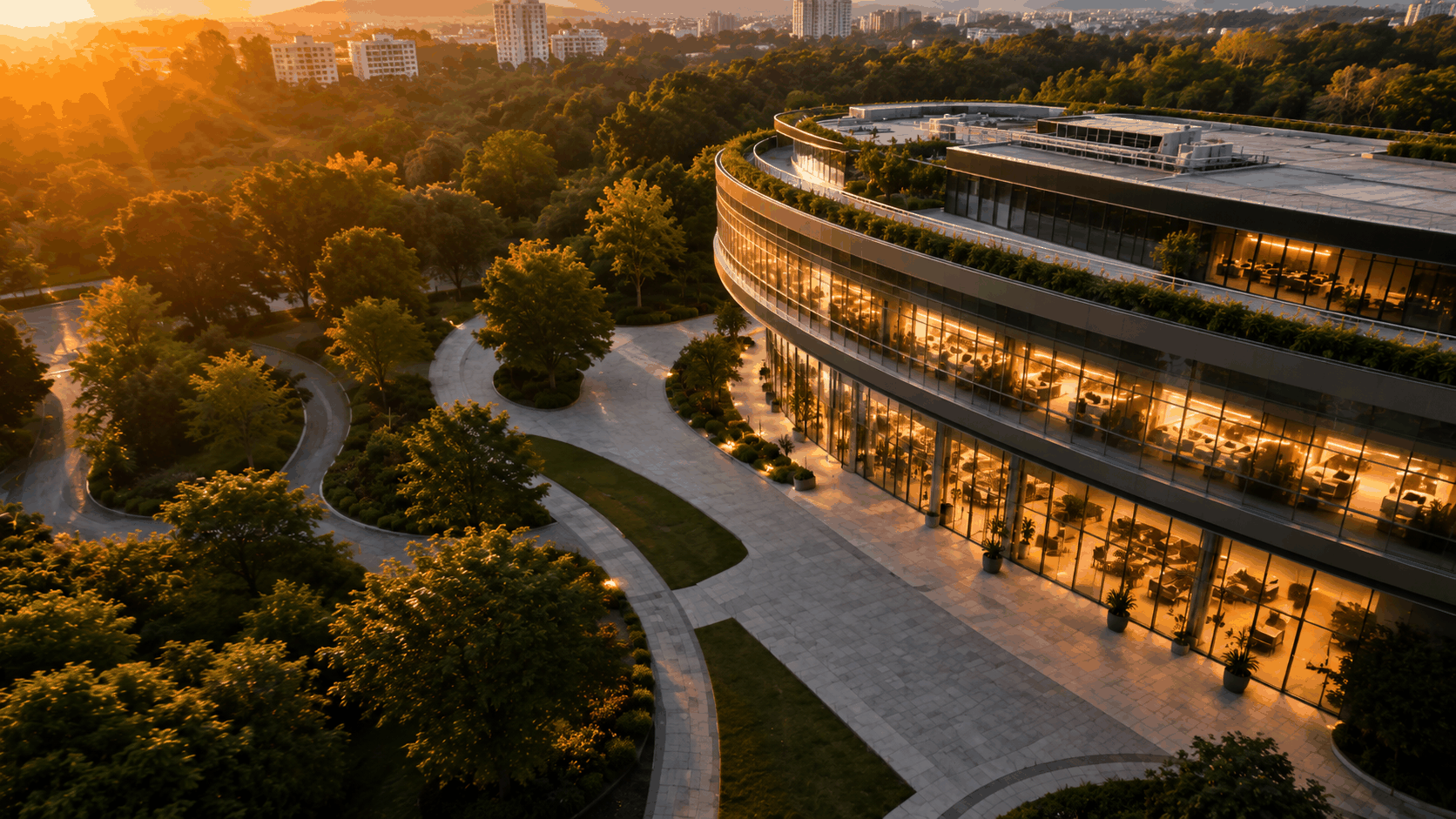 Vista aérea de un edificio curvo y sus jardines delimitados, luz de atardecer